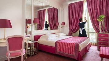 Una camera d'albergo con un letto grande, una scrivania, una sedia, una cassettiera e uno specchio.