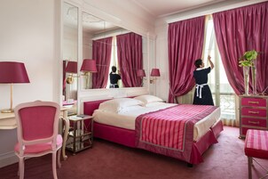 Una camera d'albergo con un letto grande, una scrivania, una sedia, una cassettiera e uno specchio.