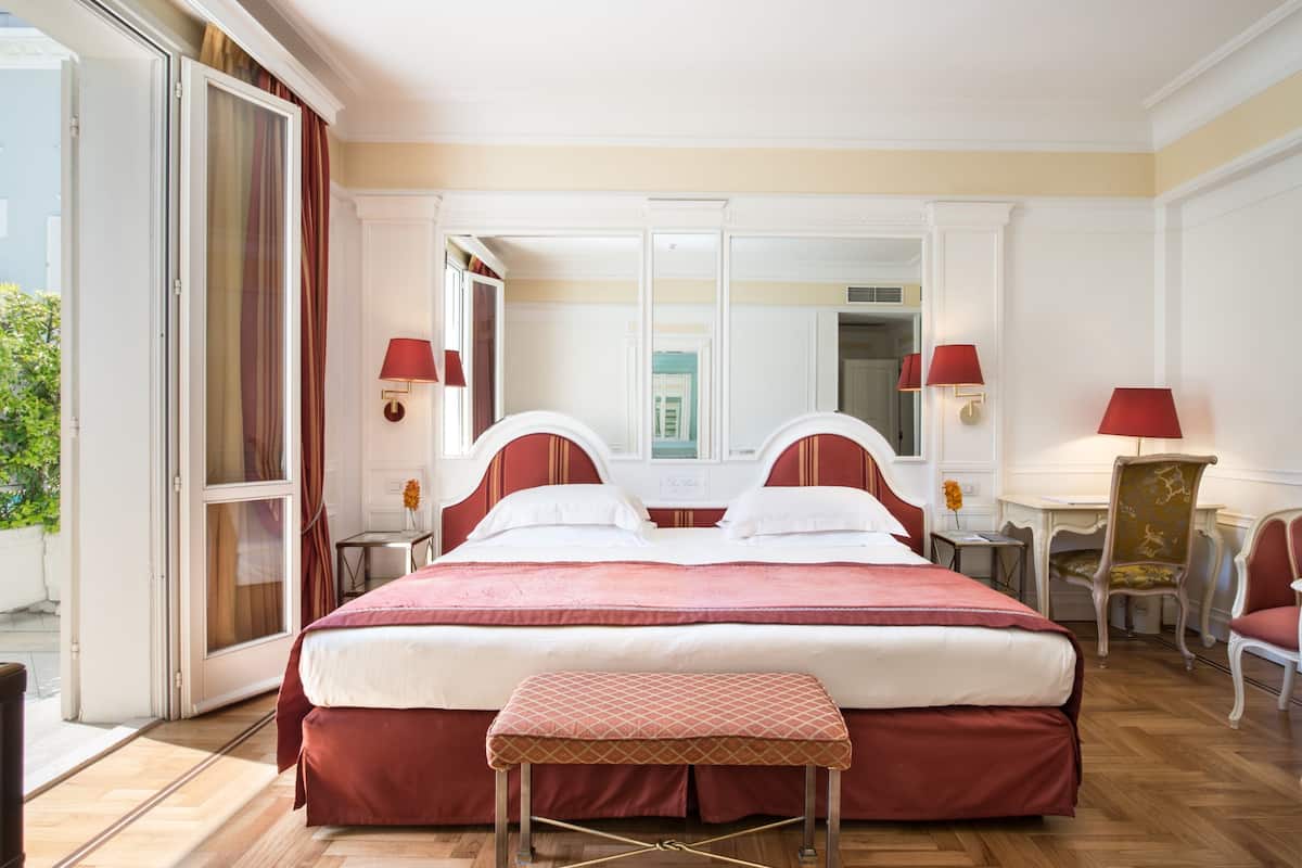 Habitación de hotel con una cama grande, un área de descanso con una silla, un escritorio y un espejo.