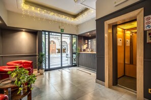 Welcome to our lobby, featuring a reception desk, comfortable seating area, and a lush potted plant.