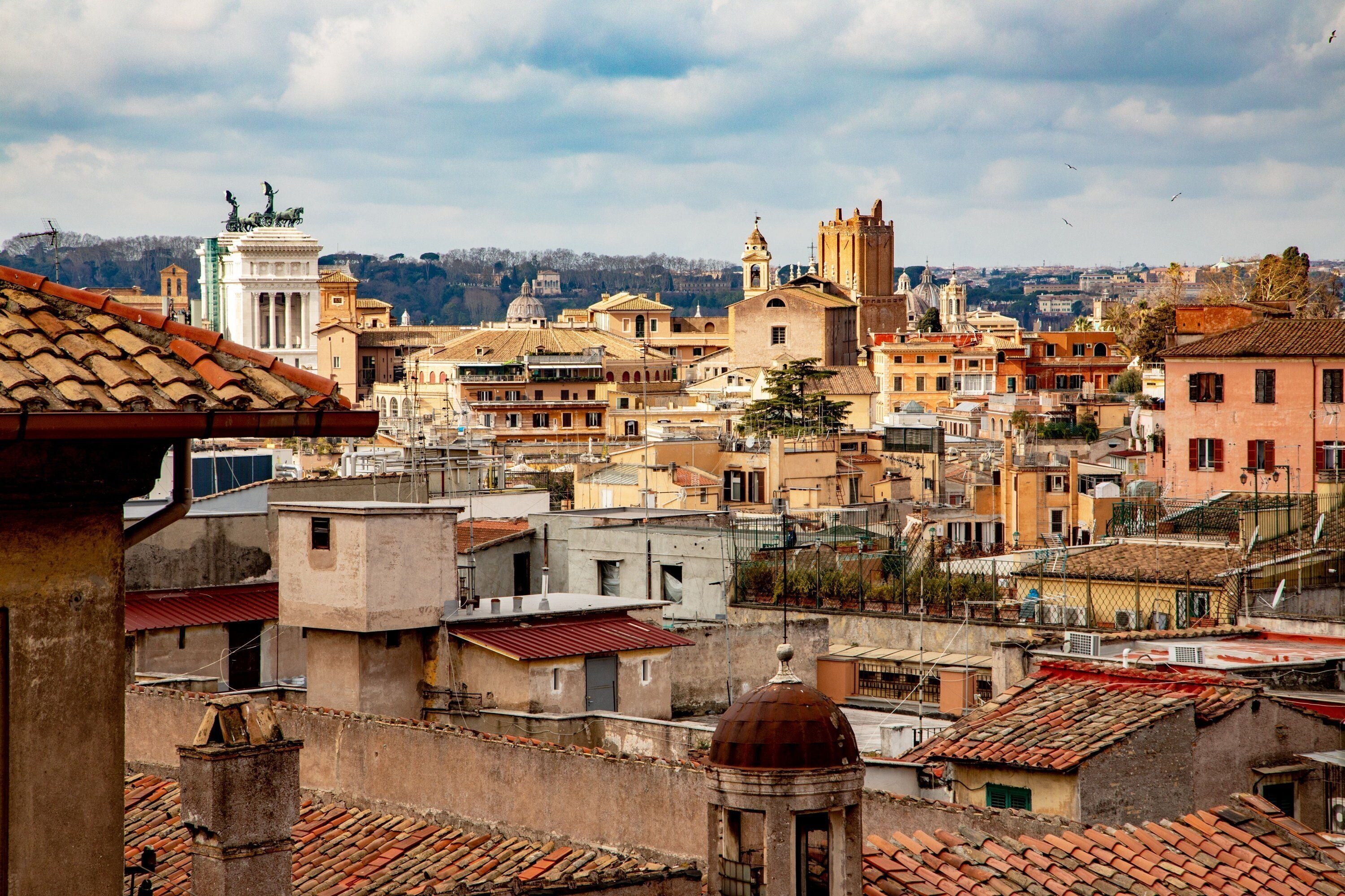 A cityscape with historic buildings, a prominent dome, and a statue on a pedestal.