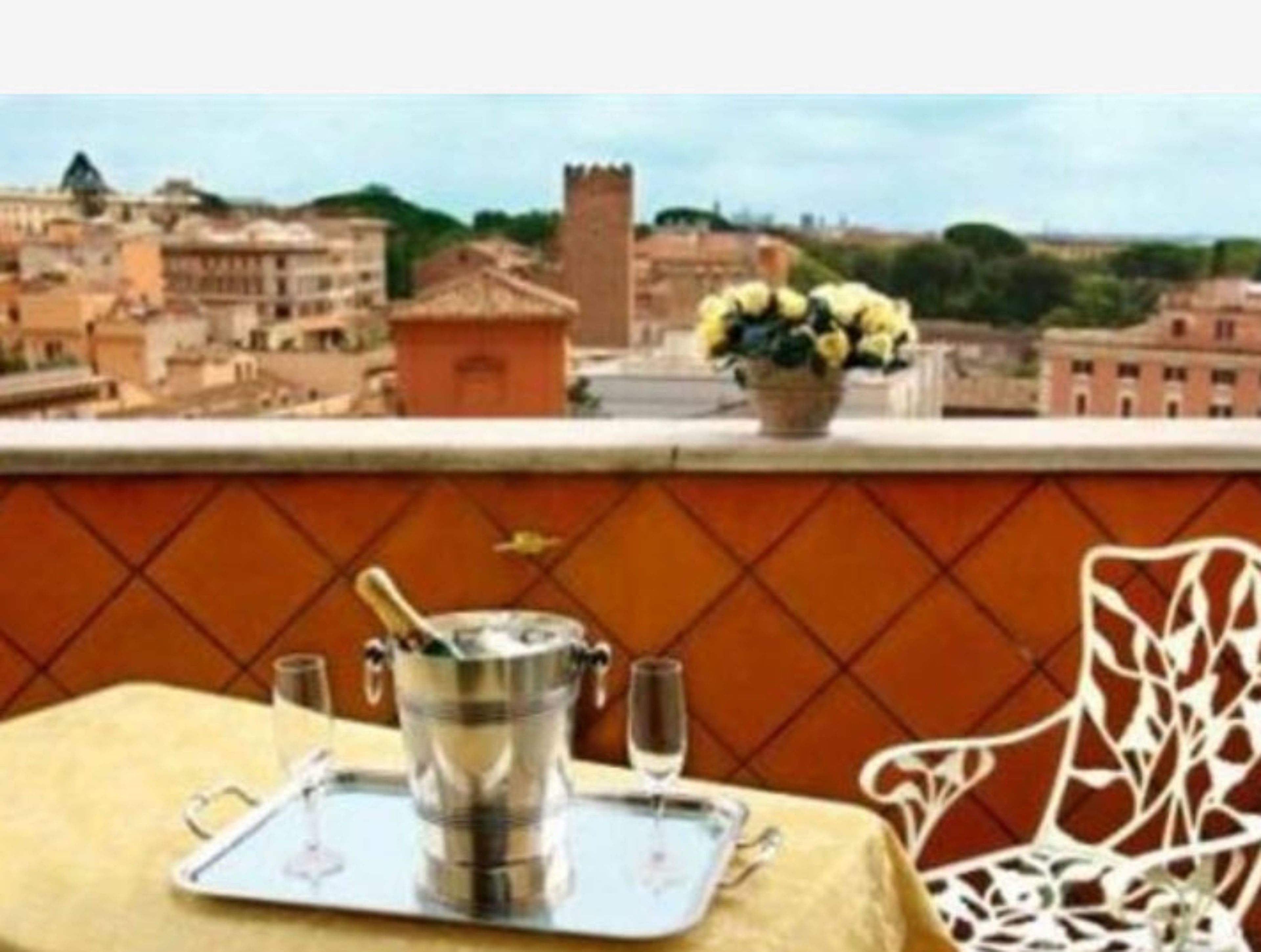 Ein Tisch mit Tablett, einer Champagnerflasche und Gläsern auf einem Balkon mit Stadtblick.
