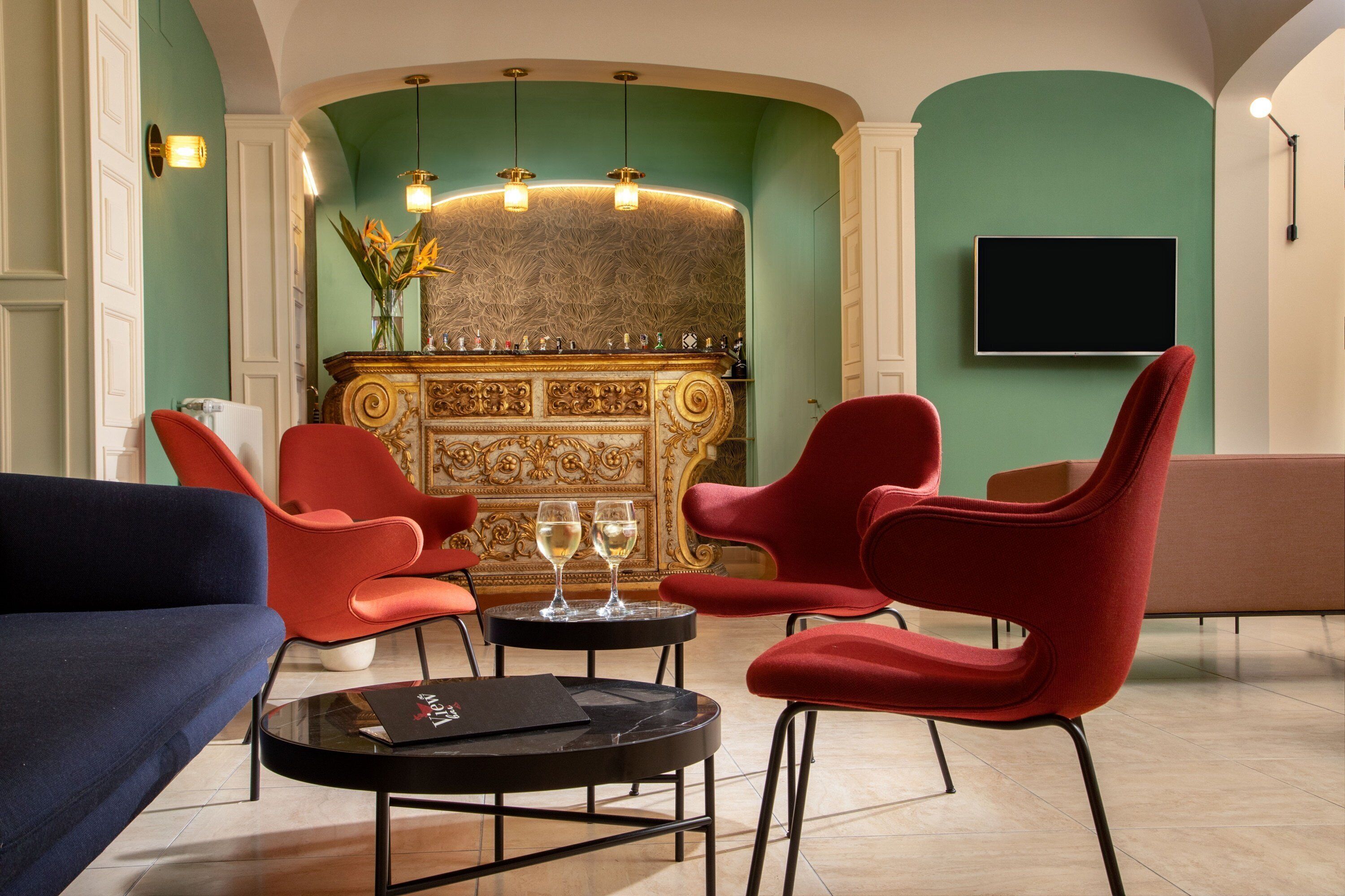 A lobby with red chairs, a blue sofa, a fireplace, and a TV on the wall.