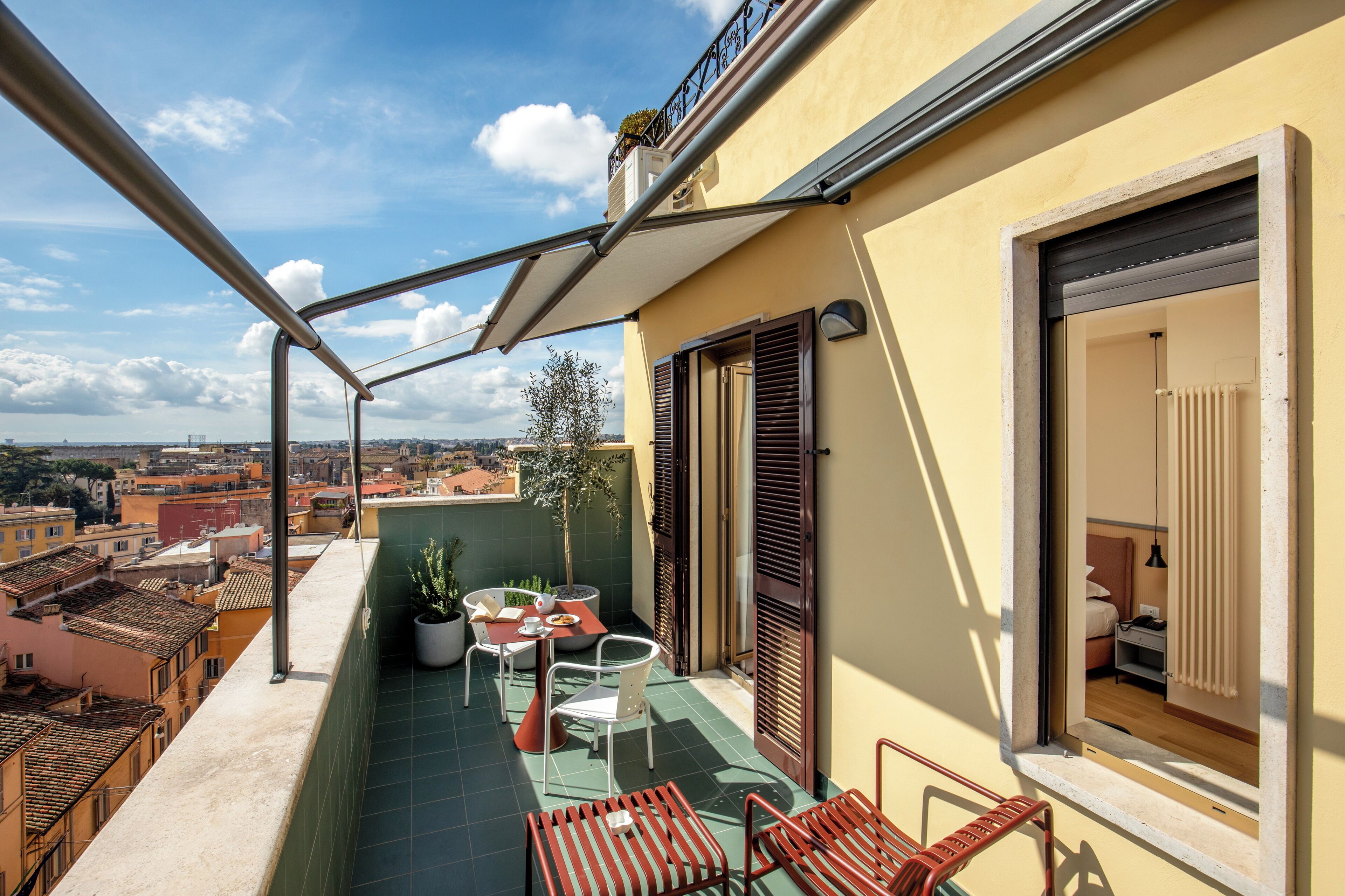 A balcony with a table, chairs, and potted plants.