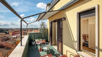 A balcony with a table, chairs, and potted plants.