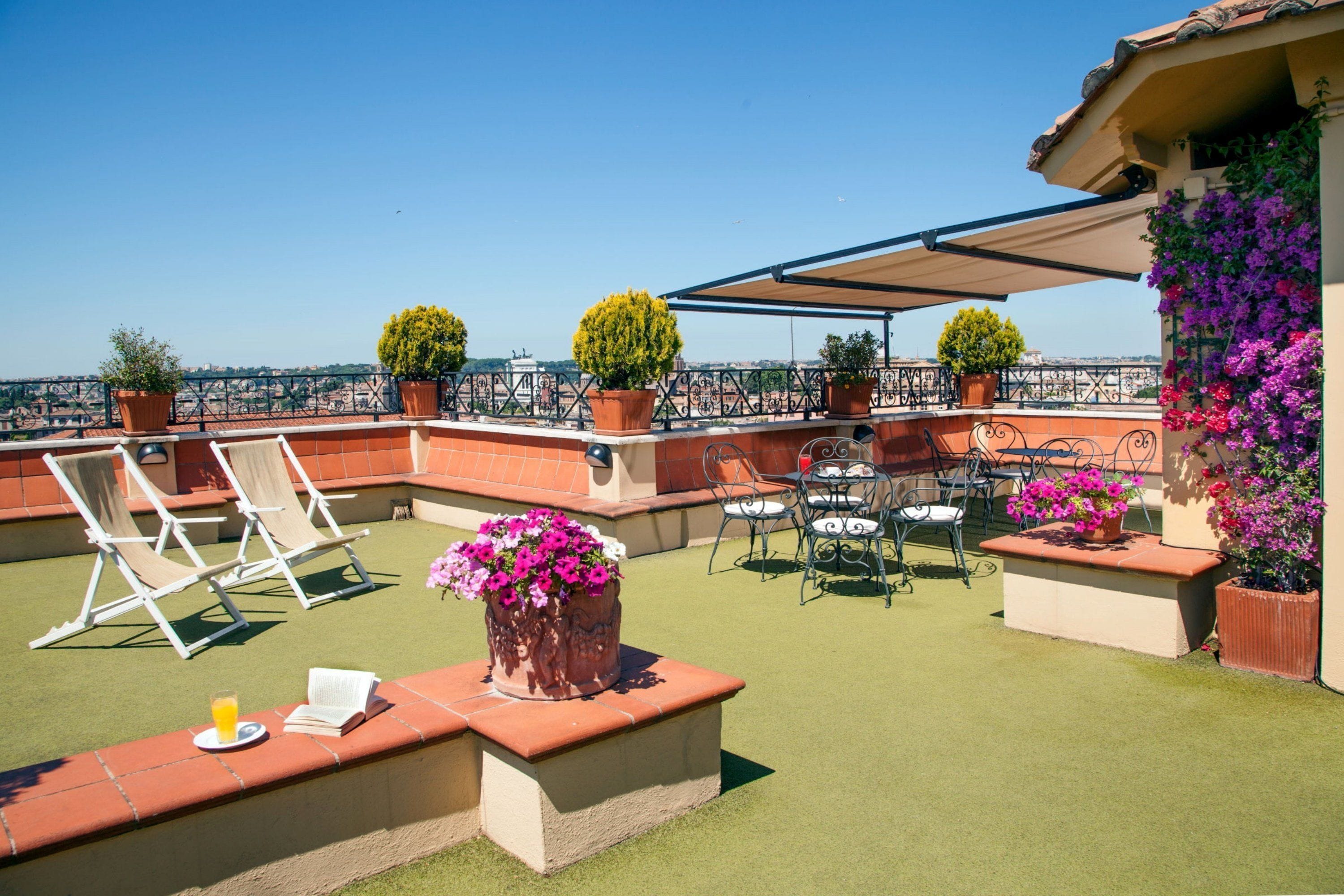 A rooftop terrace with outdoor seating, potted plants, and a view of the cityscape.