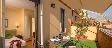 A balcony with a table, chairs, and a bed inside a room.