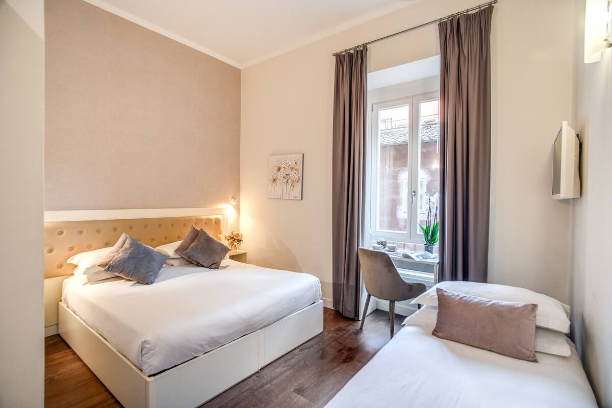 A hotel room with two beds, a desk, and a chair.