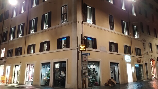 Un edificio de varios pisos con ventanas iluminadas y entrada en la planta baja.