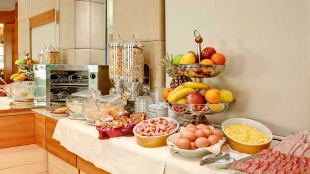 A buffet setup with various food items including fruits, eggs, and meats. - Hotel Memphis (Rome)