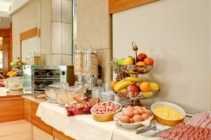 A buffet setup with various food items including fruits, eggs, and meats.