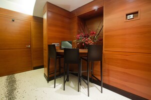 A wooden-paneled room with a desk, two chairs, and a laptop.
