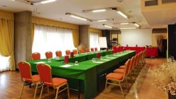 Un salón de conferencias con una larga mesa, sillas y una pantalla para proyector.