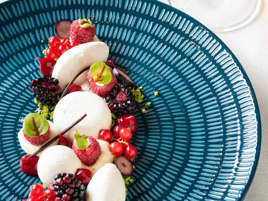 Un piatto dessert con diversi frutti e un bicchiere di vino.