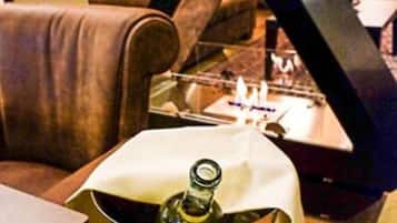 Una poltrona in pelle, una bottiglia di vino e un piccolo tavolino con una candela.