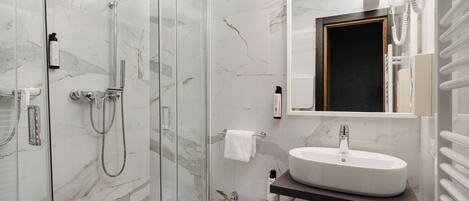 Un baño moderno con ducha de vidrio, lavamanos pedestal y un bidé.