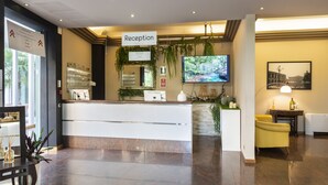 Ett väntrum med en receptionsdisk, en tv och en skylt som visar att det är receptionen.