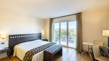 Une chambre d’hôtel comprenant un lit, une table de chevet, un banc et une petite table avec des chaises.