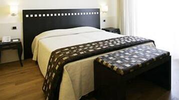 Una habitación de hotel con cama, mesitas de noche y un banco.