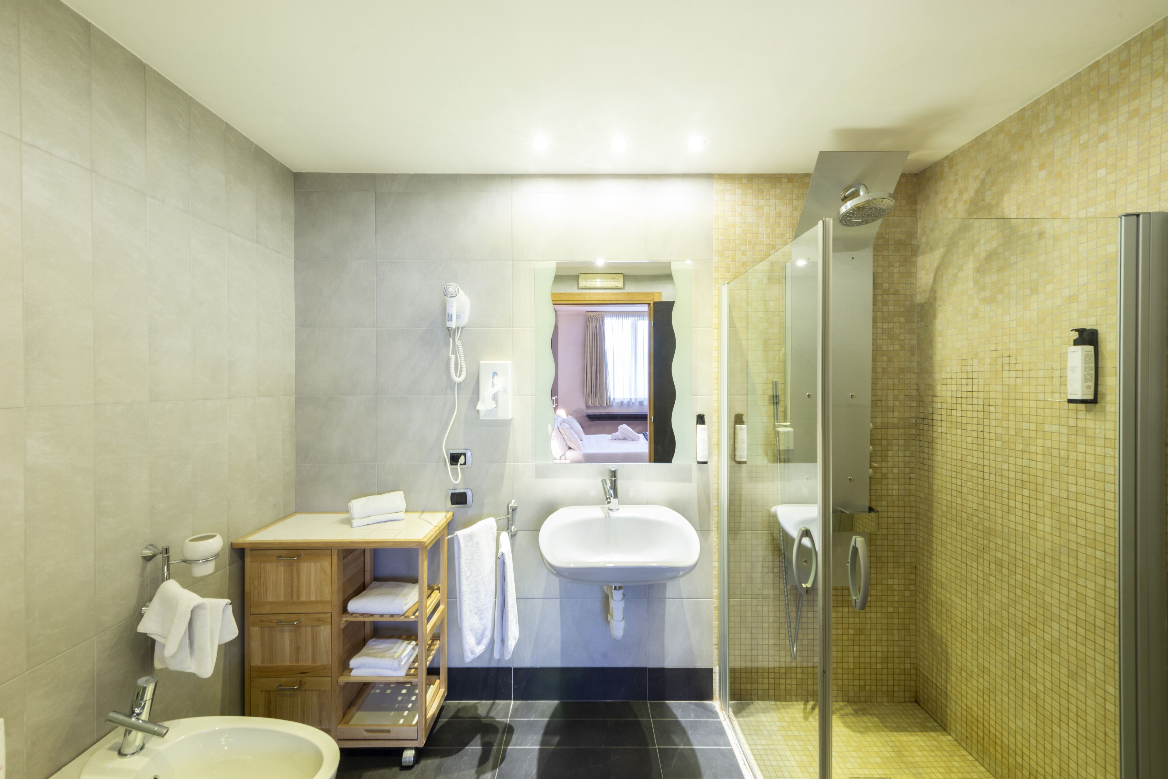 A modern bathroom with a sink, mirror, and shower.