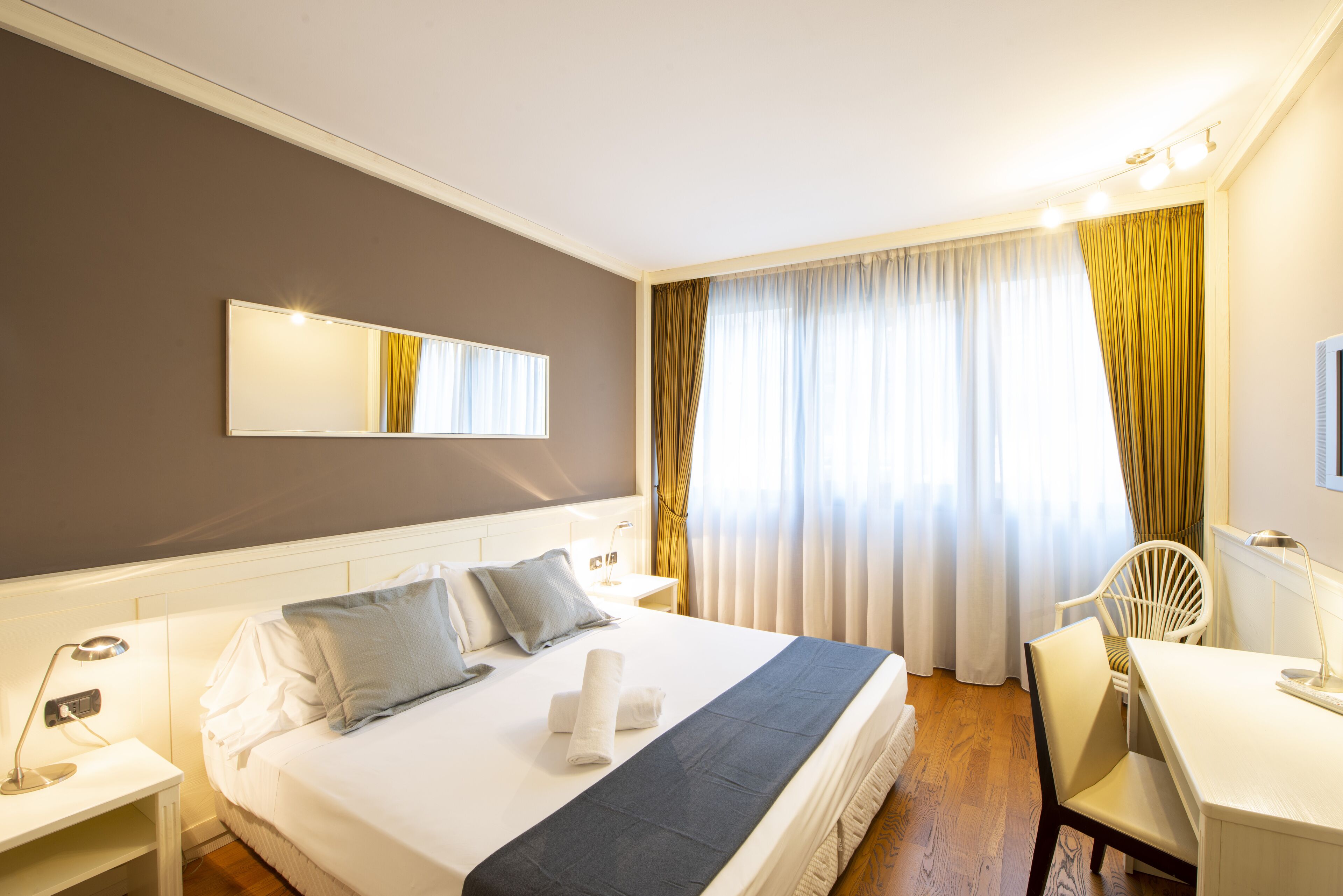Una habitación de hotel con una cama grande, un escritorio y una silla.