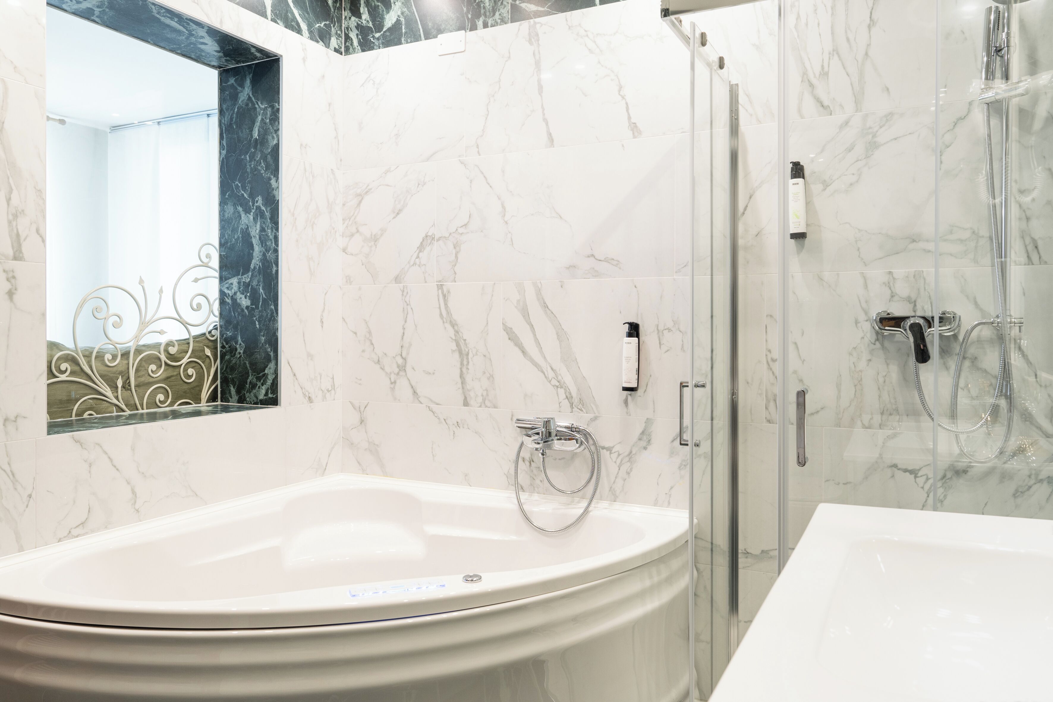A bathroom with a large bathtub, a shower, and a glass-enclosed shower area.