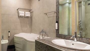 A modern bathroom with a bathtub, a sink, and a toilet. There is a towel rack above the bathtub and a mirror above the sink.