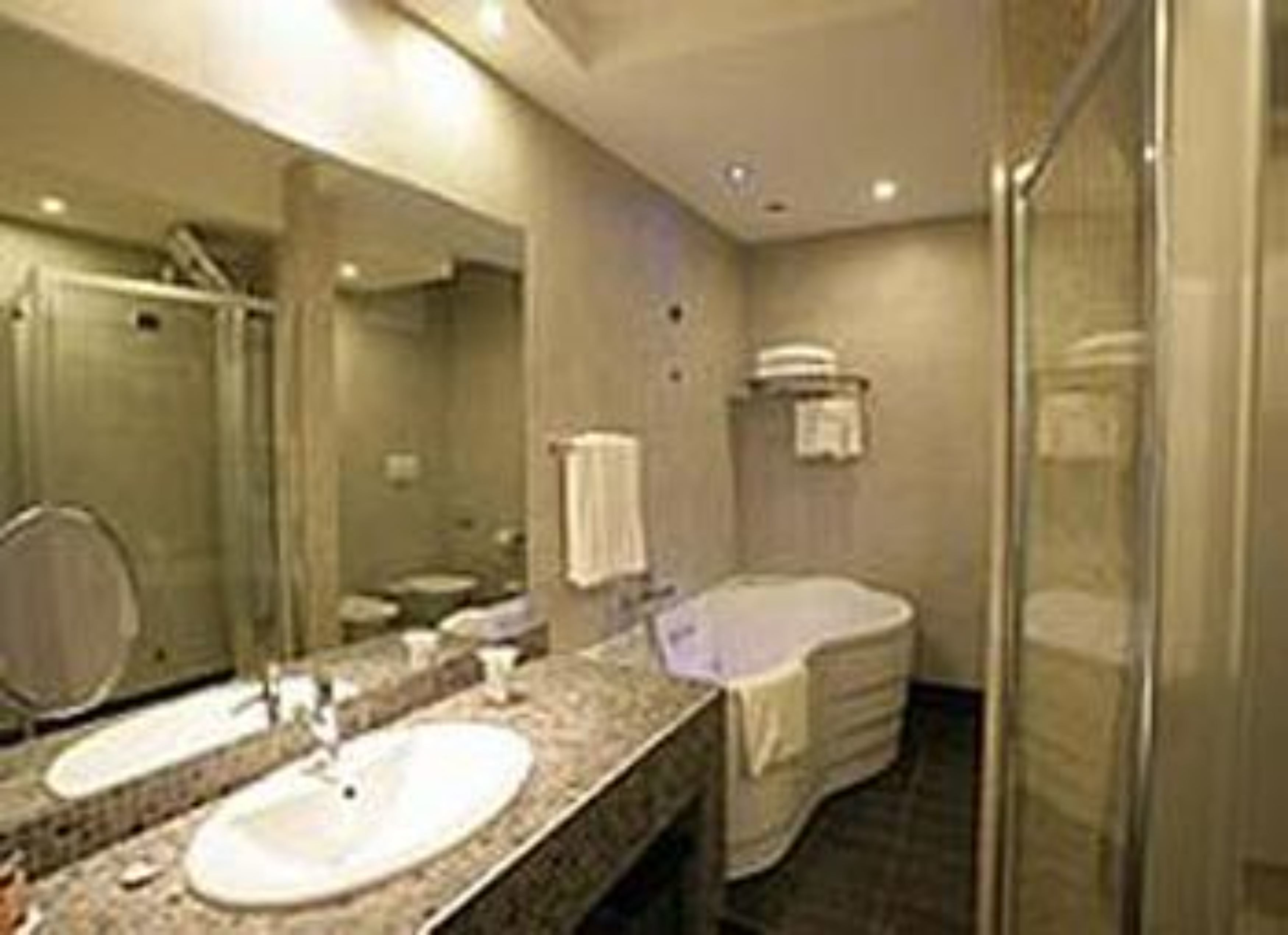 A modern bathroom with a large mirror, two sinks, a shower, and a toilet.