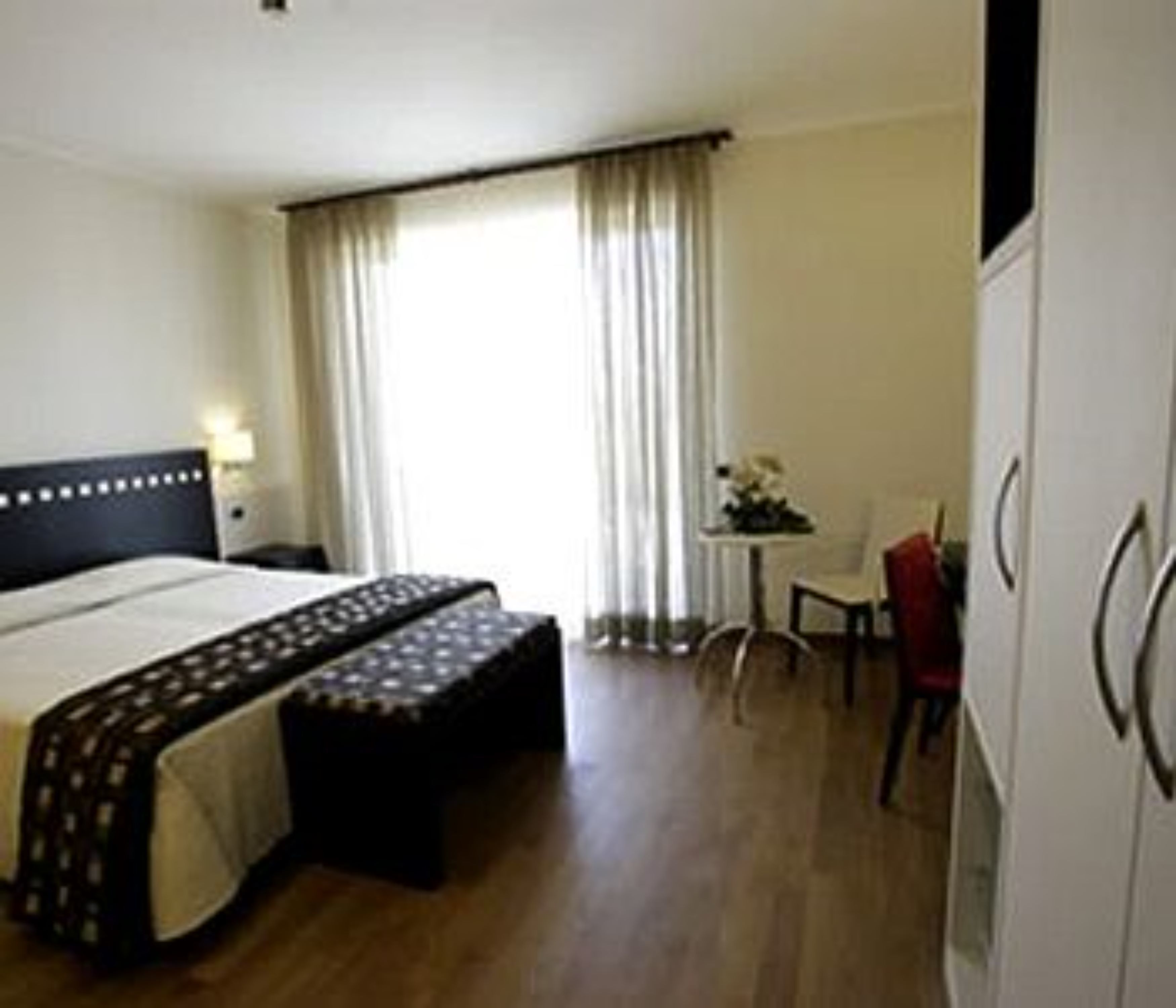 Una habitación de hotel con cama, escritorio, silla y armario.