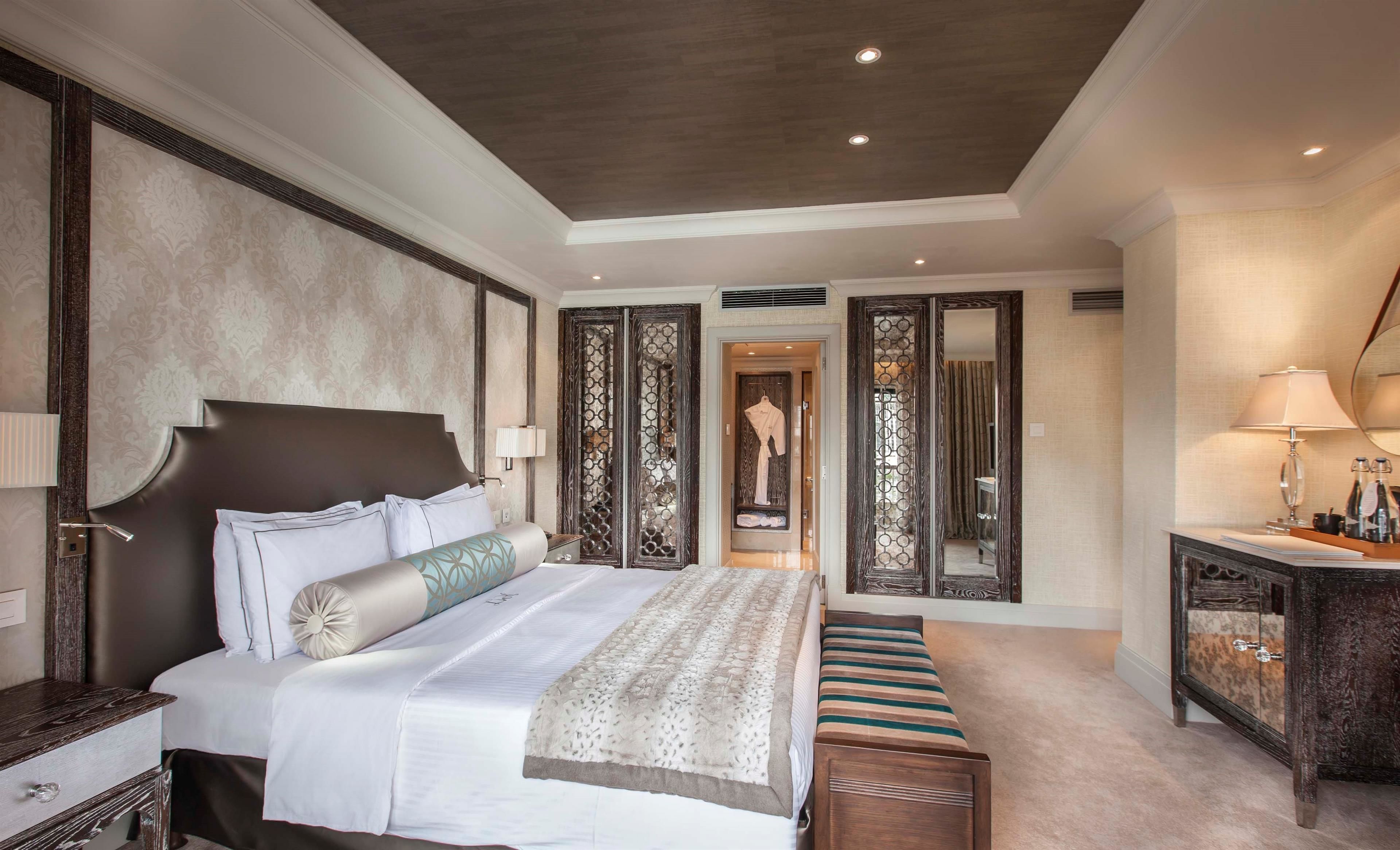 Une chambre spacieuse avec un grand lit, une table de chevet, une commode et un miroir.