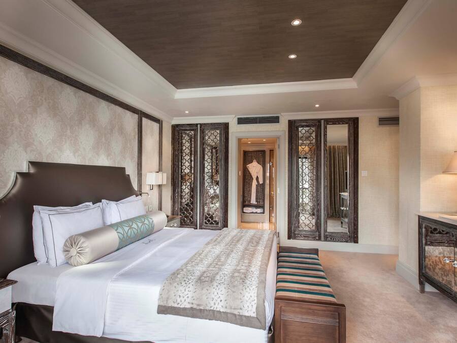 Une chambre spacieuse avec un grand lit, une table de chevet, une commode et un miroir.