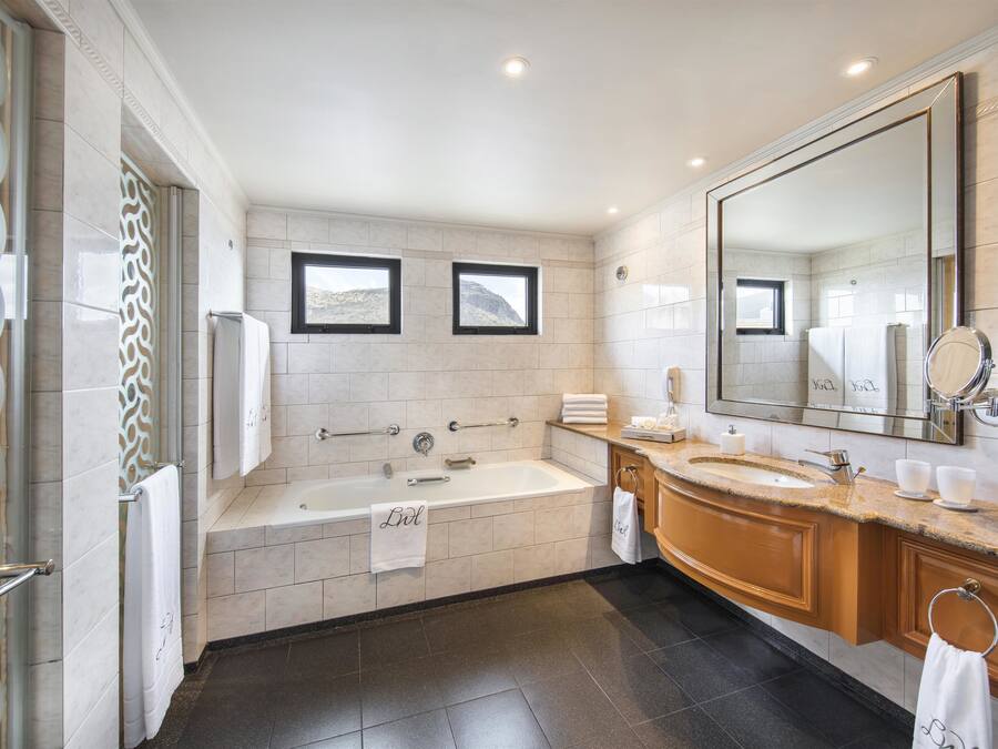 A modern bathroom with a bathtub, a large mirror, and a vanity with a sink.
