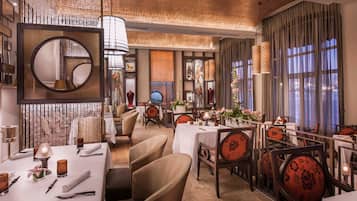 A restaurant with round tables, chairs, and hanging lamps.