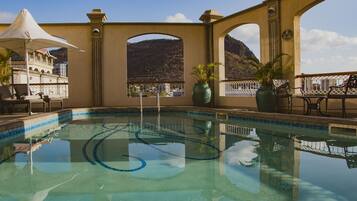 Una piscina al aire libre, sombrillas, tumbonas