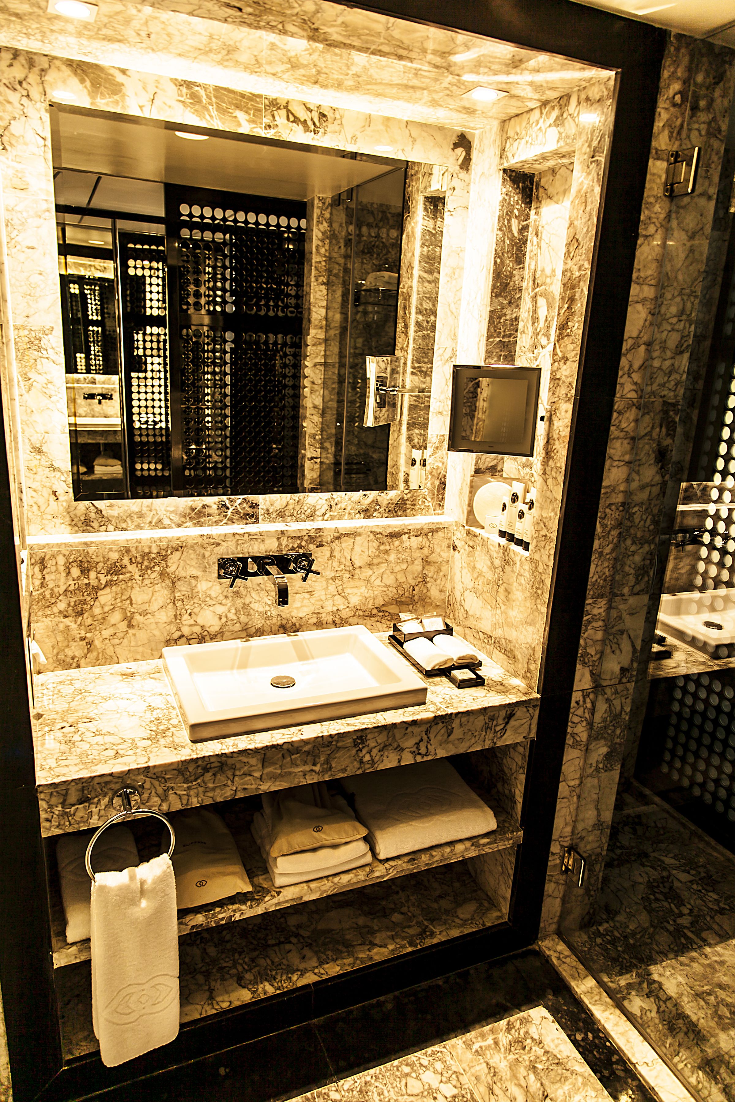 A marble bathroom with a sink, mirror, and towel rack.
