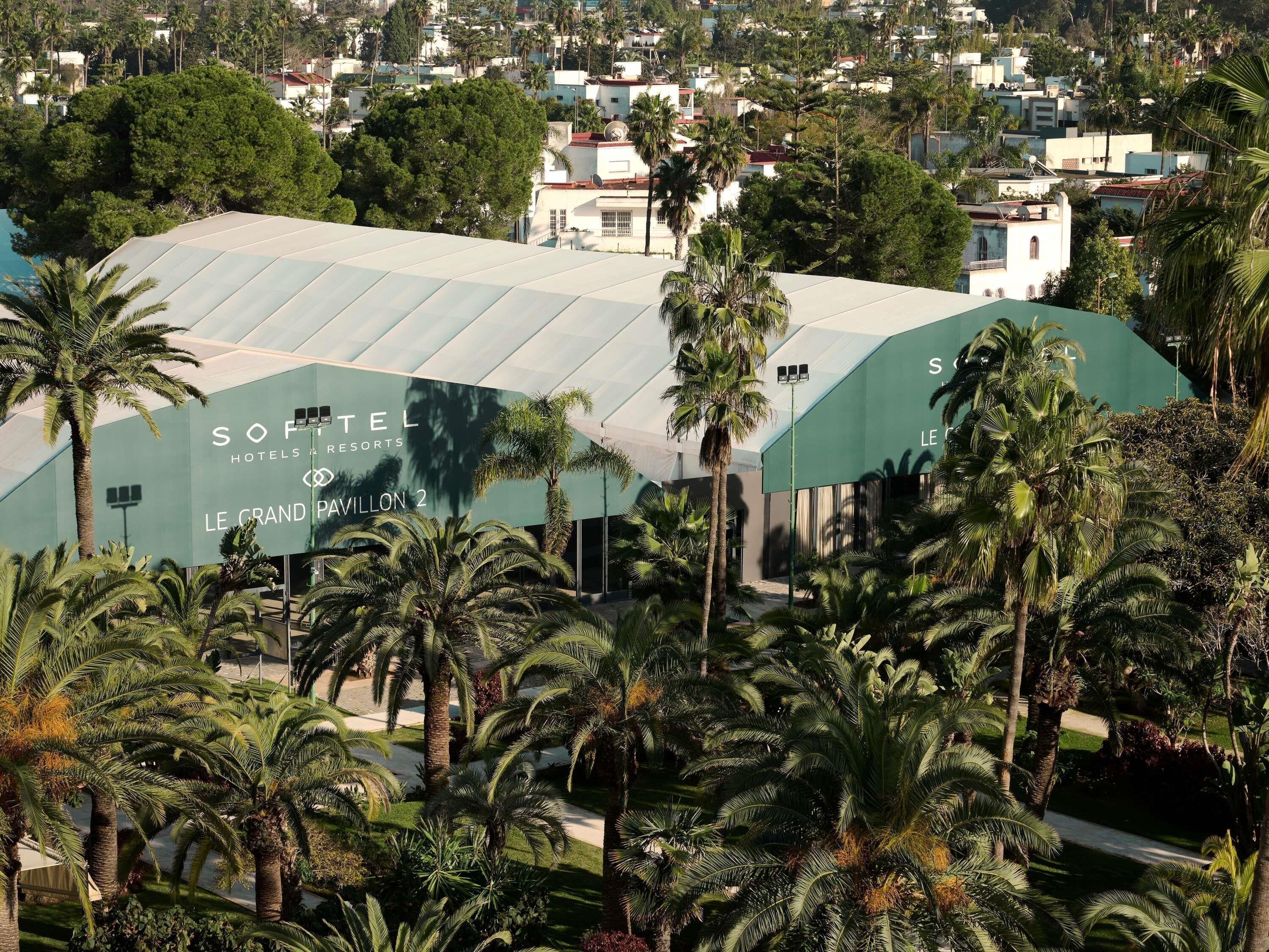 Un hotel con una estructura grande y moderna, rodeado de palmeras y otra vegetación.