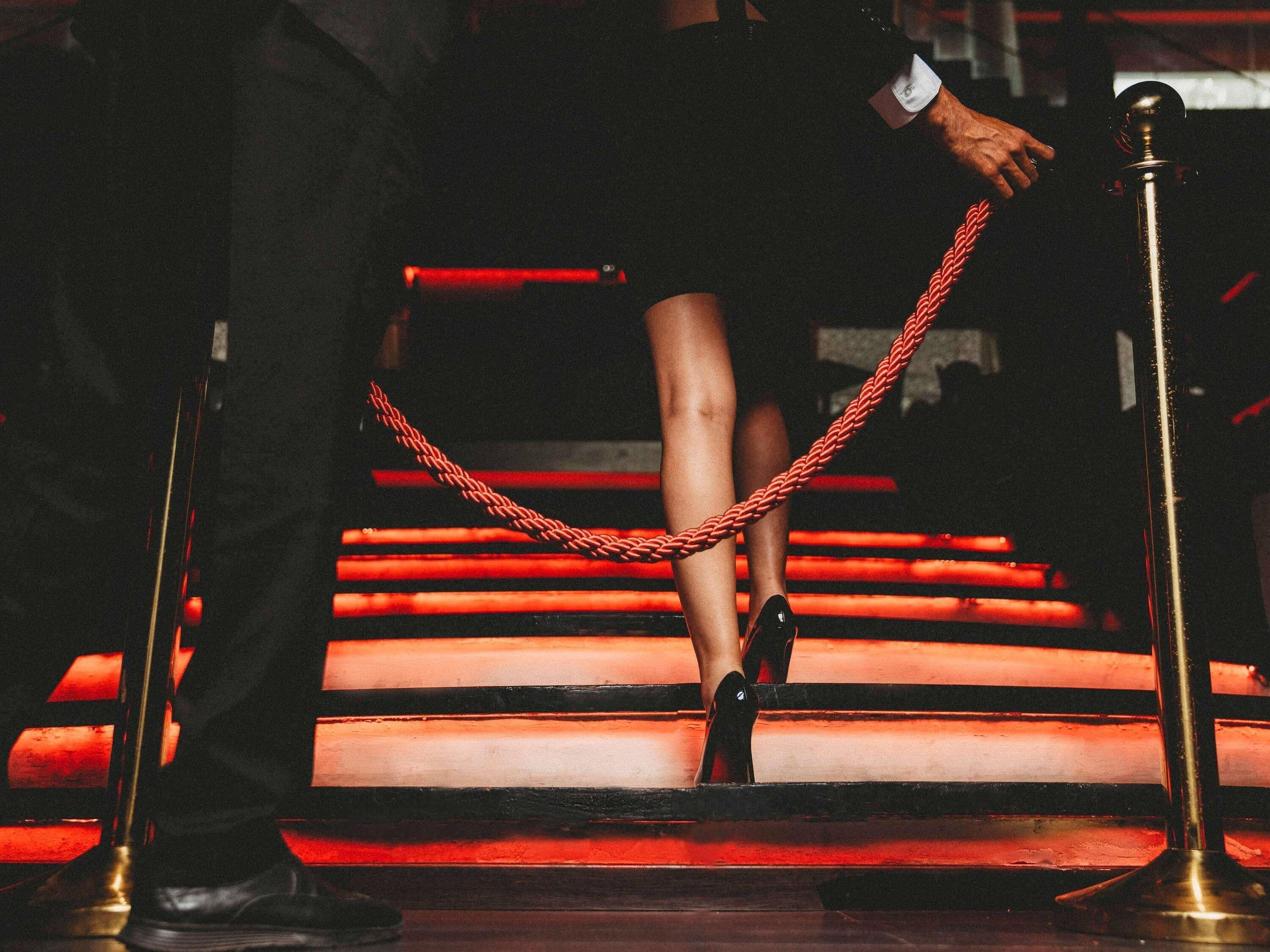 Una persona bajando una escalera con barandillas y una barrera de cuerda, ambas rojas.