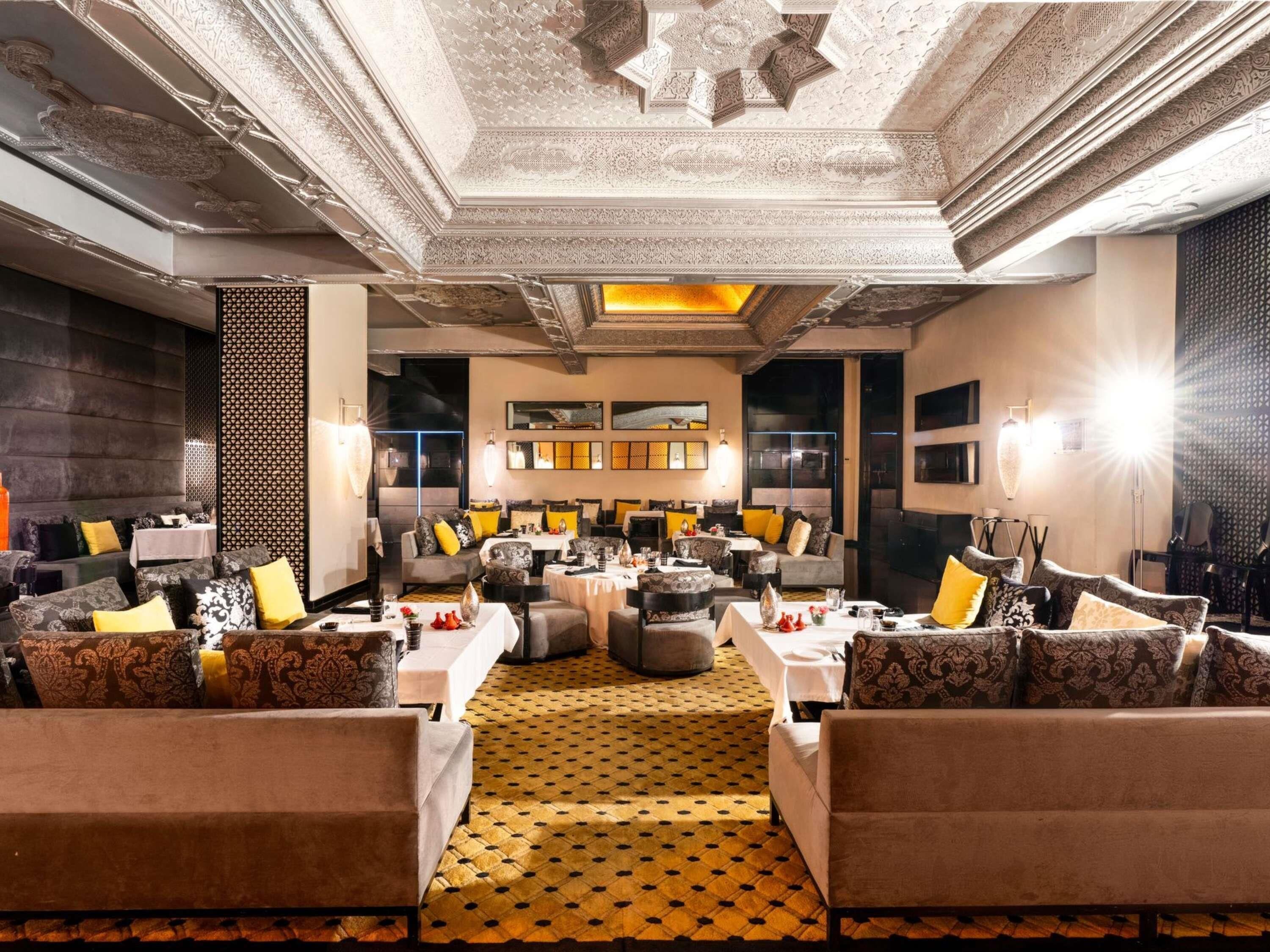 A spacious lounge area with multiple seating arrangements, a patterned floor, and decorative ceiling elements.