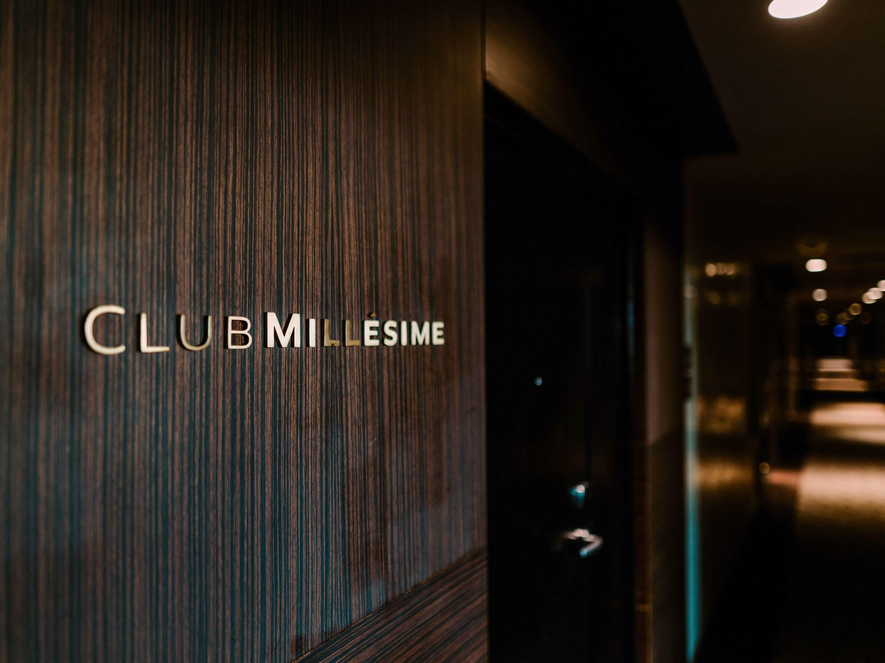 A modern interior with a wooden panel wall and a sign reading "CLUB MILLESIME".