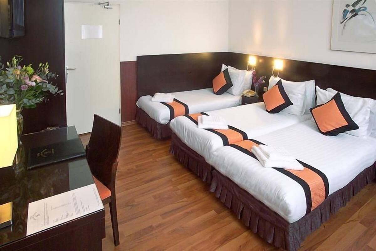 A hotel room with two beds, a desk, and a chair.