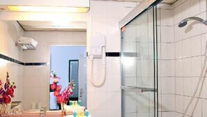 A bathroom with a glass-enclosed shower, a sink with a mirror, and a toilet. - Hotel Falcon Plaza (Amsterdam)