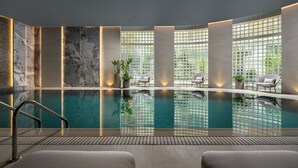 An indoor swimming pool with a clear view of the sky through large windows, surrounded by marble walls and modern seating. - InterContinental Athénée Palace Bucharest by IHG (Bucharest)