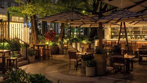 An outdoor patio area with tables and chairs, umbrellas, and potted plants. - InterContinental Athénée Palace Bucharest by IHG (Bucharest)