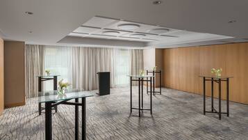 A conference room with glass tables, a podium, and a large window with curtains.