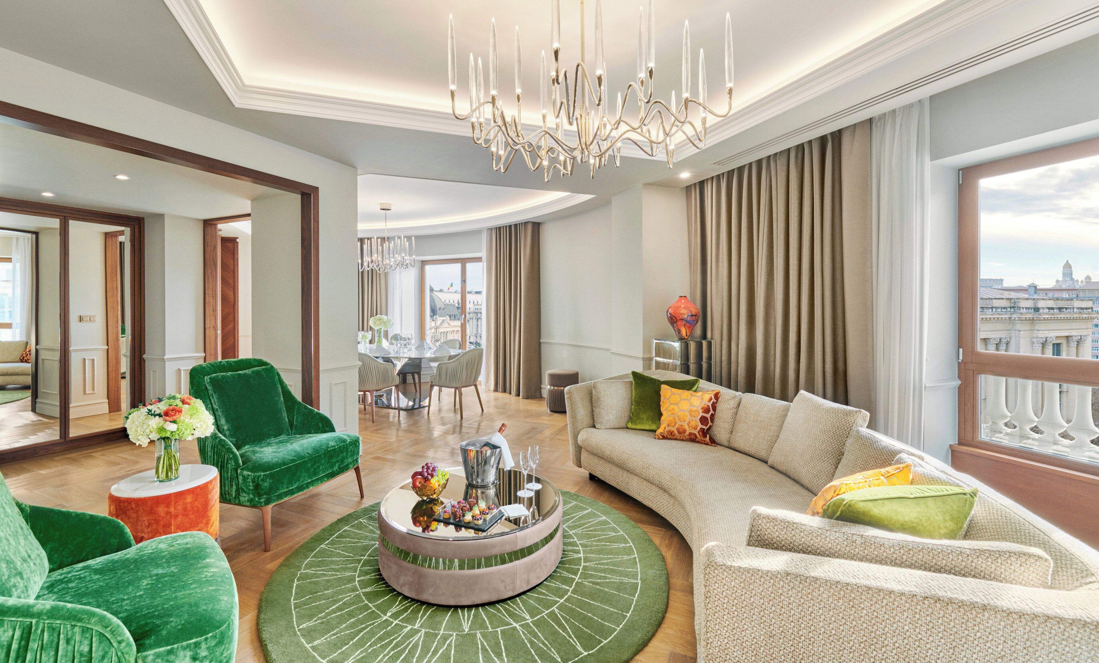 Zona saló àmplia amb un llum modern, una taula de cafè rodona amb objectes decoratius, un butac armchair verd i un sofà beix amb coixins de colors.