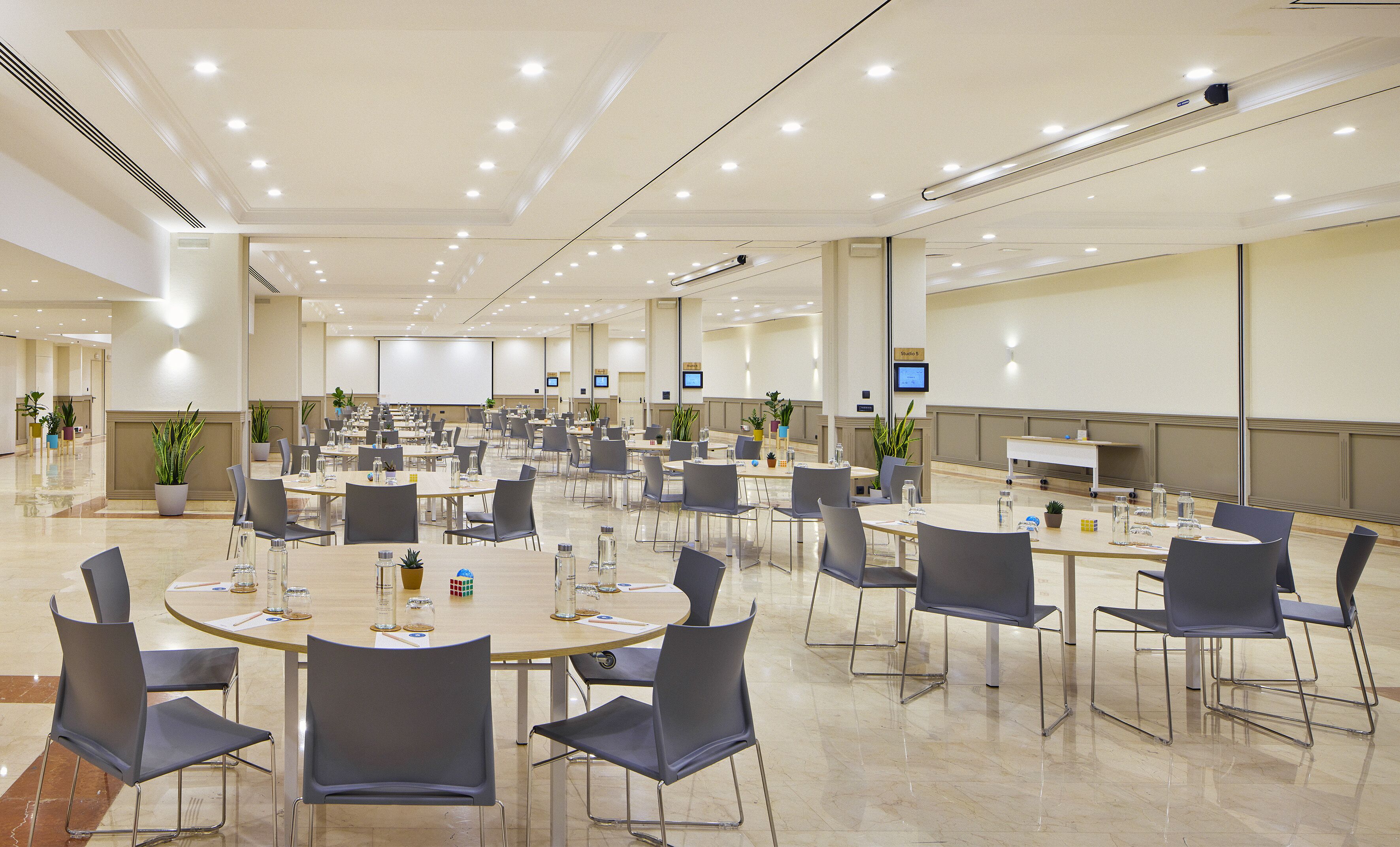 Une grande salle de conférence dotée de nombreuses tables et chaises, ainsi que de bouteilles d’eau et de plaques nominatives.