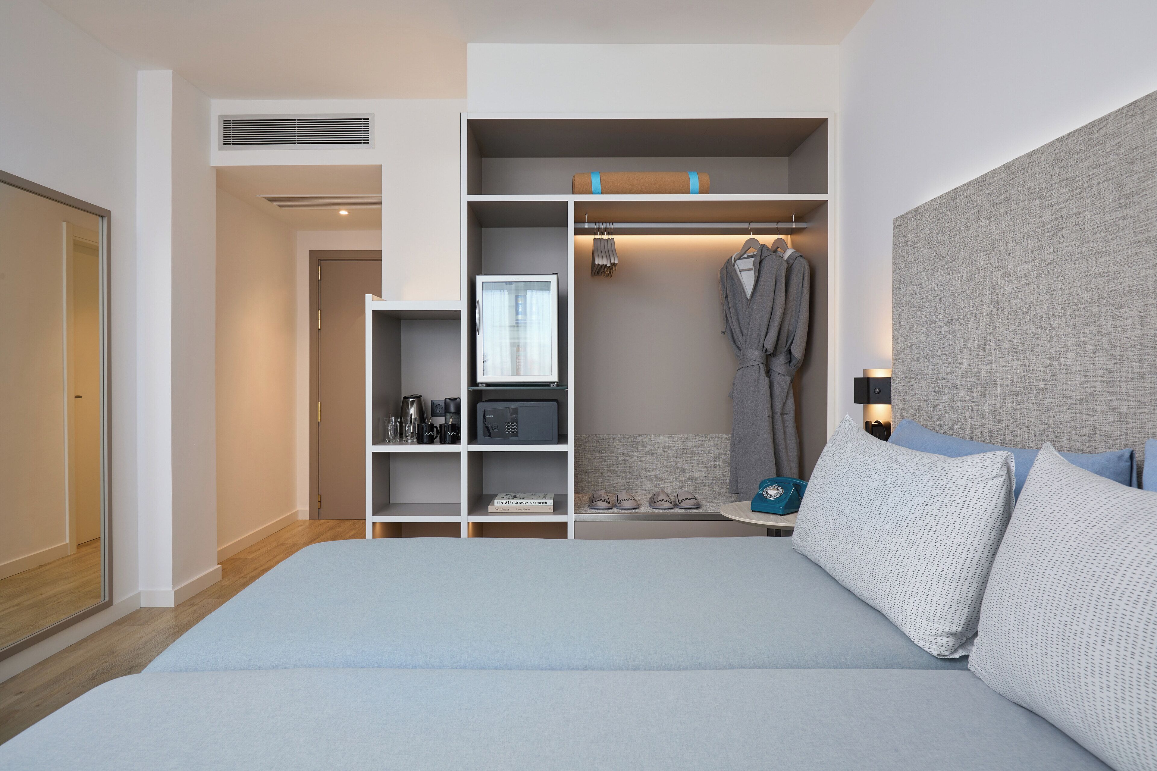 A modern bedroom with a large bed, a walk-in closet, and a built-in TV.