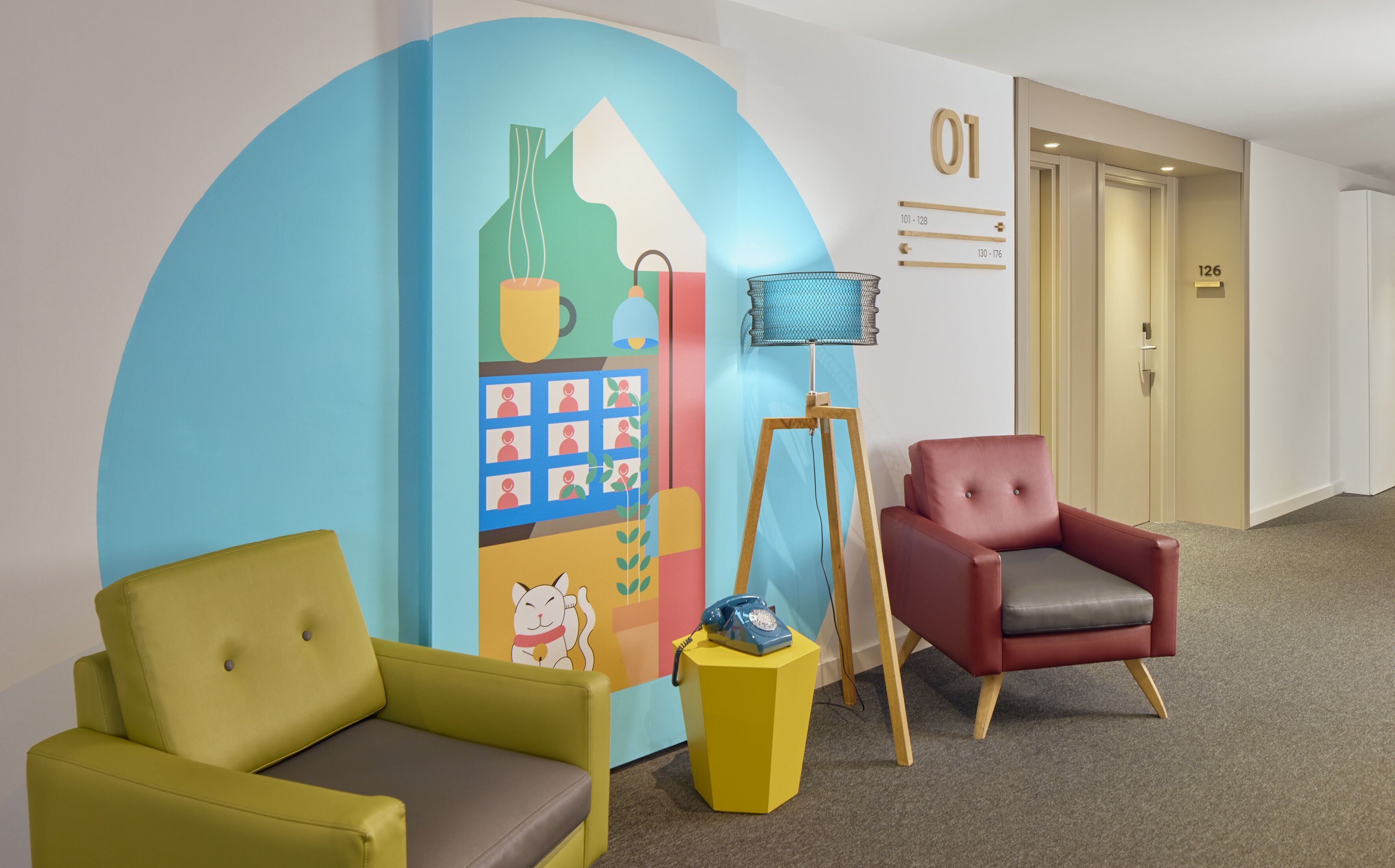 Un vestíbulo de hotel con dos sillones, un mural colorido, un teléfono y una puerta marcada '01'.