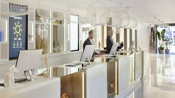 A modern reception area with glass partitions, white furniture, and decorative items.