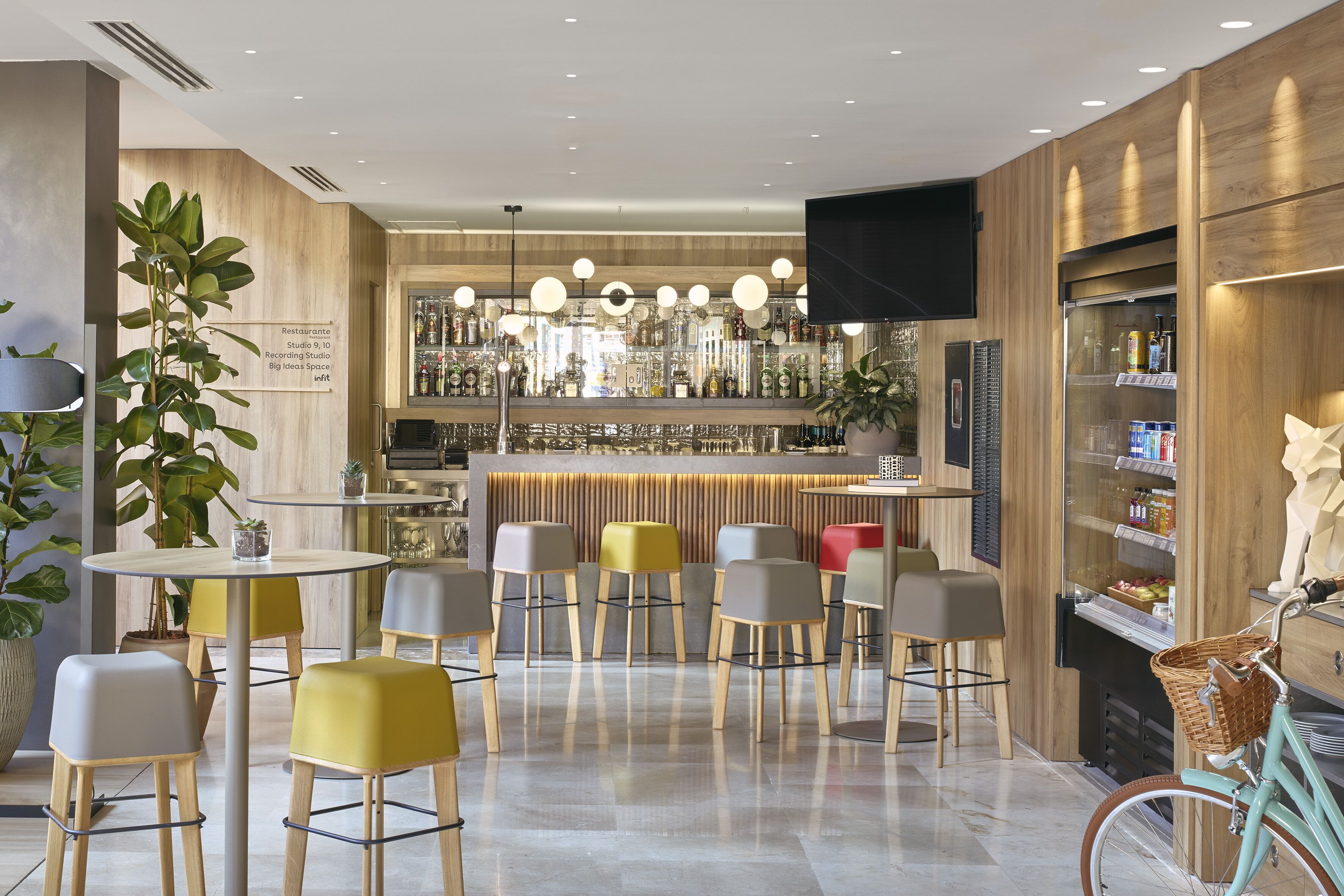 A modern bar area with wooden accents, a variety of seating options, and a visible bar counter with bottles.